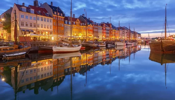 Nyhavn Harbor Explore Denmark Ever fantasized about ambling along the quaint, flagstone pathways of a metropolis that looks like it's been taken right out of a Hans Christian Andersen storybook? Or perhaps, imagined yourself in the midst of vibrant music scenes and ancient Viking heritage? Welcome to Denmark! This Scandinavian beauty is not just about Lego bricks and butter cookies. With its perfect blend of old-world charm, modern architecture, rich history, artistic prowess, and stunning natural wonders - it's truly an explorer's paradise. And if you're wondering where to start your Danish adventure from... well! You're at the right place. Because we've compiled for you a guide on 12 best places to visit in Denmark. By the time we wrap up this adventure, you'll have witnessed where sandy beaches kiss the ocean at sunset. You'll have explored art galleries brimming with creativity and soaked in iconic tunes.